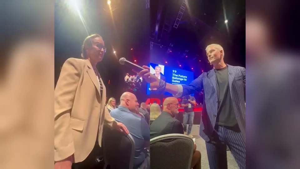 Ryan Serhant hands Amanda Conroy the microphone in the audience at AREC 2024, Gold Coast